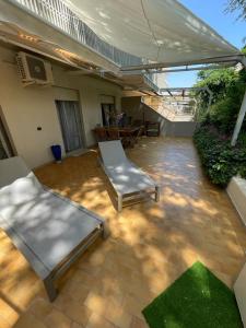 eine Terrasse mit 2 Stühlen, einem Tisch und einem Sonnenschirm in der Unterkunft Casa Roberta con favolosa terrazza privata in Caorle