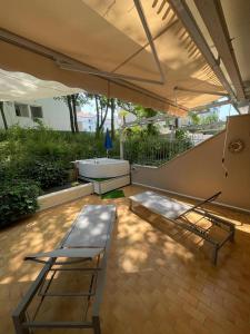 un patio con sombrilla, banco y bañera en Casa Roberta con favolosa terrazza privata, en Caorle