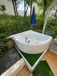 una vasca da bagno bianca con un ombrellone sull'erba di Casa Roberta con favolosa terrazza privata a Caorle