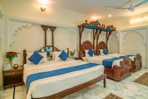 a bedroom with two beds with blue and white sheets at Swaroop Vilas - Lake Facing Boutique Hotel in Udaipur