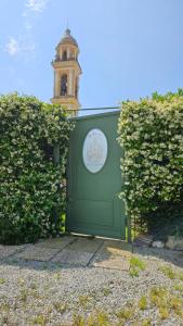 a green gate with a clock tower in the background at La Rocca Maison de Charme in Moneglia