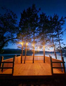 a wooden deck with two benches and trees at night at Nomad Domes in Rugineşti