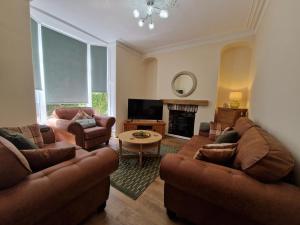 a living room with two couches and a fireplace at Hidden Beauty! 5 Bedroom House near town centre with Bike Store in Merthyr Tydfil