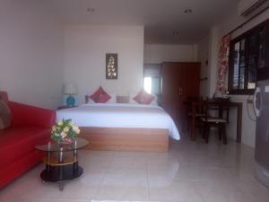 1 dormitorio con 1 cama grande y 1 sofá rojo en Da Bungalows en Kata