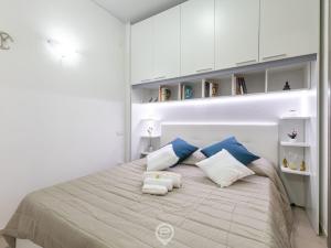 a white bedroom with a bed with blue and white pillows at Zaffiro Apartment in Quartu SantʼElena