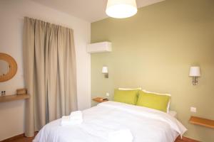 Schlafzimmer mit einem Bett mit weißer Bettwäsche und grünen Kissen in der Unterkunft Twin House Spetses in Spetses
