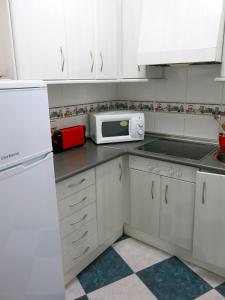 a kitchen with white cabinets and a white microwave at Oasis junto al mar in Torre del Mar