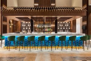 a bar with green chairs and a blue bar counter at Wyndham Bukhara in Bukhara