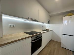a kitchen with white cabinets and a sink and a refrigerator at Apartamento Rancho Suizo in Platja d'Aro