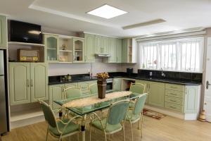 a kitchen with green cabinets and a table and chairs at Casa Garavaglia in Bento Gonçalves