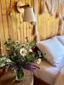 eine Vase mit Blumen auf einem Tisch neben einem Bett in der Unterkunft House Girska Rika in Korchin