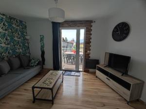 ein Wohnzimmer mit einer Couch, einem Tisch und einer Uhr in der Unterkunft Gite terrasse sur Vercors in Saint-Marcellin