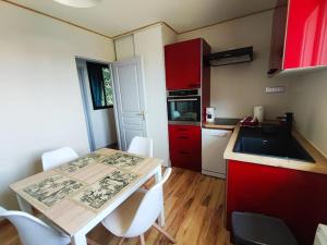 eine Küche mit roten Schränken und einem Tisch mit weißen Stühlen in der Unterkunft Appartement terrasse du Vercors piscine et spa in Saint-Marcellin