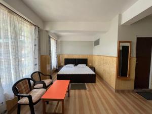 Habitación con cama, mesa y sillas. en Hotel Palbheu Inn, en Namchi