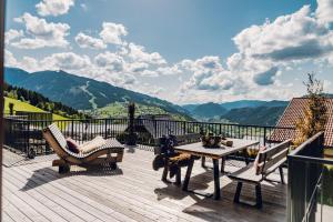 a wooden deck with a table and chairs and mountains at Chalet W - auf der Planai -zu jeder Jahreszeit in Schladming