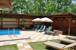 埃格爾的住宿－Garden Villa Zsóry，一个带椅子和遮阳伞的庭院和一个游泳池