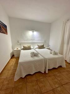 1 dormitorio con 2 camas con sábanas blancas en AT Espalmador Formentera rustick en Es Pujols