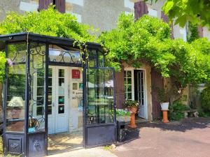 ein Gewächshaus aus Glas vor einem Gebäude in der Unterkunft Hôtel La Flambée in Bergerac