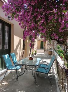 un tavolo e sedie sotto un albero con fiori viola di Villa Lidi a Stavros