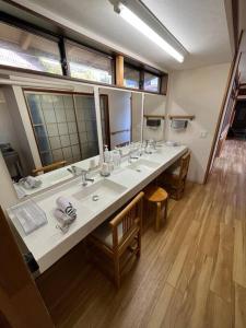 uma casa de banho com 3 lavatórios e um espelho grande em オオヤシロSTAY旅音 em Izumo