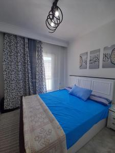 a bedroom with a blue bed and a window at Two Bedrooms for Families only Chalet Sia Lagoon Golf Porto Marina للعائلات فقط شاليه غرفتين كريستال لاجون جولف بورتو مارينا in El Alamein