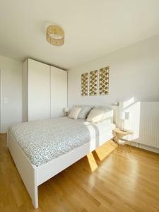 a white bedroom with a bed and a wooden floor at Suite Riviera - Vue Disneyland in Chessy