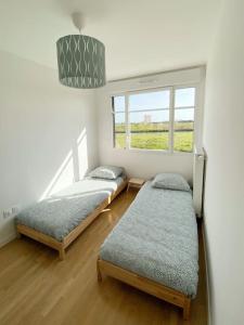 two beds in a room with a window at Suite Riviera - Vue Disneyland in Chessy