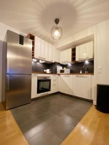 a kitchen with a stainless steel refrigerator and white cabinets at Suite Riviera - Vue Disneyland in Chessy