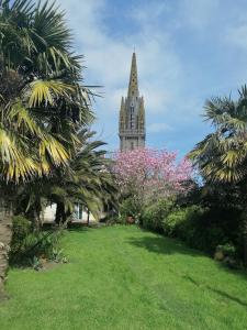 a church steeple in the distance with trees and flowers at L'air Breton in Goulven