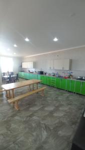 a large kitchen with a wooden table and green cabinets at Гостевой дом АНЖЕЛИКА с бассейном in Tsandrypsh