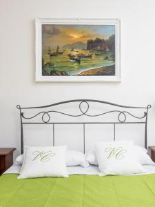 obraz nad łóżkiem z zieloną pościelą i poduszkami w obiekcie Villa Cristina - De Vivo Realty Piano di Sorrento w mieście Piano di Sorrento