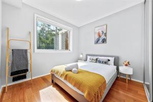 a white bedroom with a bed and a window at cosy Chatswood retreat, conventience location in Sydney
