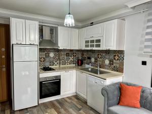 UğurluにあるSuitesの白いキャビネット、シンク、ソファ付きのキッチンが備わります。 +3枚の写真