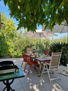 a patio with a table and chairs and an umbrella at Mas de la Petite Jeanne in Grimaud