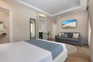 um quarto branco com uma cama grande e um sofá em Télos Rooms em Villasimius