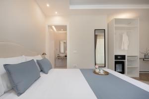 a white bedroom with a large white bed with blue pillows at Télos Rooms in Villasimius