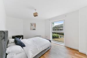 a white bedroom with a bed and a large window at Amazing 2 Bedroom Flat In Canary Wharf in London