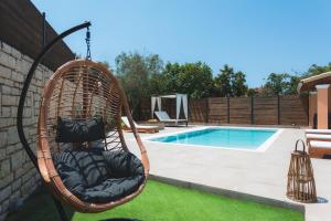 a swinging chair next to a swimming pool at Villa Bella Donna Corfu in Corfu