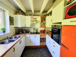 una cucina con armadi bianchi e frigorifero arancione di La petite maison dans la prairie a Libin