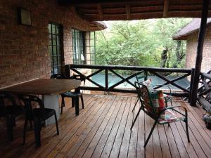 a porch with a table and chairs on a wooden deck at HomeBase Kruger in Marloth Park