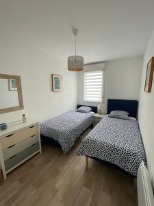een slaapkamer met 2 bedden en een spiegel bij Maison neuve agréable et très bien située in Mimizan