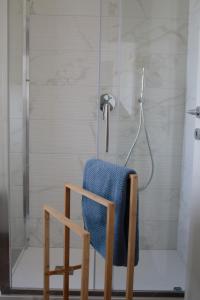 y baño con ducha y toalla azul sobre una silla. en La Milanese - New apartment - Closed to Metrò ISOLA, en Milán