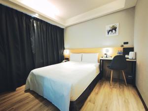 a bedroom with a bed and a desk and a chair at Hub Hotel Songshan Inn in Taipei