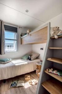 a small bedroom with a bunk bed and a window at Camping les Dunes in Le Bois-Plage-en-Ré