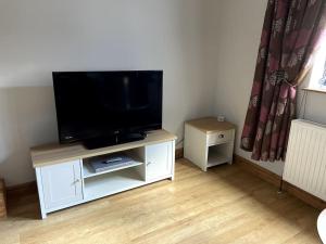 a living room with a flat screen tv on a white cabinet at Garden cottage in South Collingham