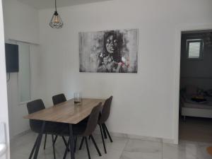 a dining room table with chairs and a painting on the wall at Apartman Marita in Kaštela