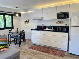 cocina con armarios blancos, mesa y nevera en חצר ברמה, en Sha'al