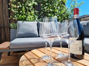 tres copas de vino sentadas en una mesa con una botella de vino en Sunny Terrace in Modern Flat with AC, en París