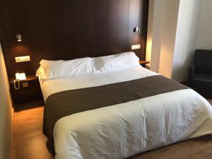 ビリャロブレドにあるHotel Castilloのベッドルーム1室(大型ベッド1台、白いシーツ、枕付)