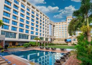 an exterior view of a hotel with a pool and palm trees at Express Inn The Business Luxury Hotel in Nashik